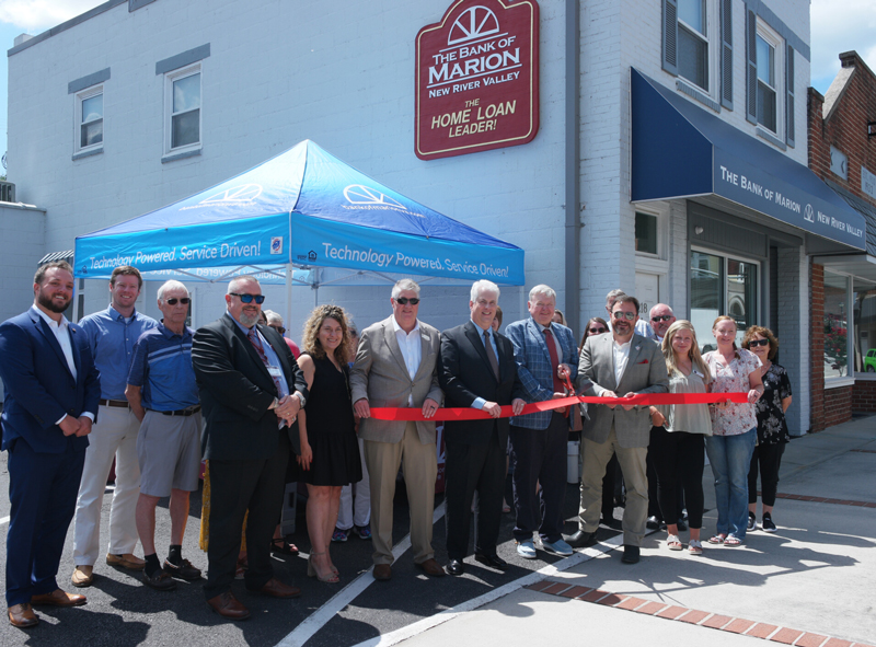 Charlie Clark, Chairman of The Bank of Marion’s Board of Directors, cuts the ribbon to officially open The Bank of Marion – New River Valley. He is assisted by Radford, Virginia Mayor, David Horton (to Mr. Clark’s left) and Chris Snodgrass, President and CEO of The Bank of Marion, (to Mr. Clark’s right.)  Mr. Snodgrass is flanked by Mark Arney, Branch Manager and Loan Officer; Mr. Arney’s wife, Susan, and Tim Carter, a member of the bank’s board of directors.