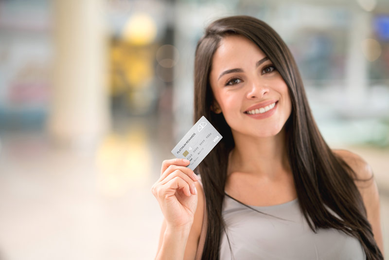 Brown haired woman holding a contactless platinum rewards credit card.